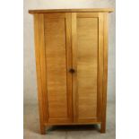 A contemporary hardwood two door floor standing cabinet, enclosing three shelves, on square