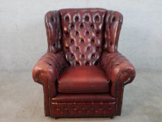 A 20th century oxblood leather Chesterfield style wingback arm chair raised on casters.