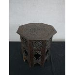 An Indian ornately carved hardwood octagonal occasional table, the top carved with a foliate design,