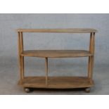An Ercol blonde elm three tier trolley bookcase, model 361, raised on wheels with remains of