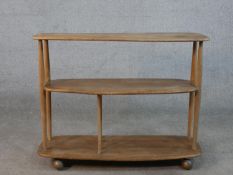 An Ercol blonde elm three tier trolley bookcase, model 361, raised on wheels with remains of