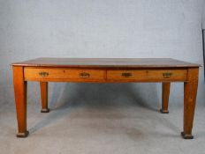 An early 20th century oak two drawer writing table raised on tapering supports terminating in square