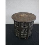A carved Indian hardwood folding occasional table, the circular top densely carved with fruiting