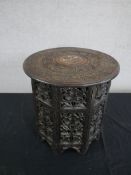 A carved Indian hardwood folding occasional table, the circular top densely carved with fruiting