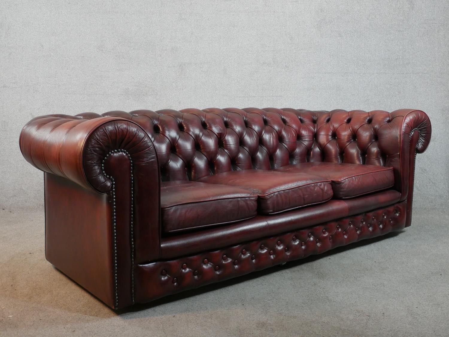 A 20th century oxblood red Chesterfield three seater settee, raised on casters, H.65 W.195 D.67cm - Image 5 of 5