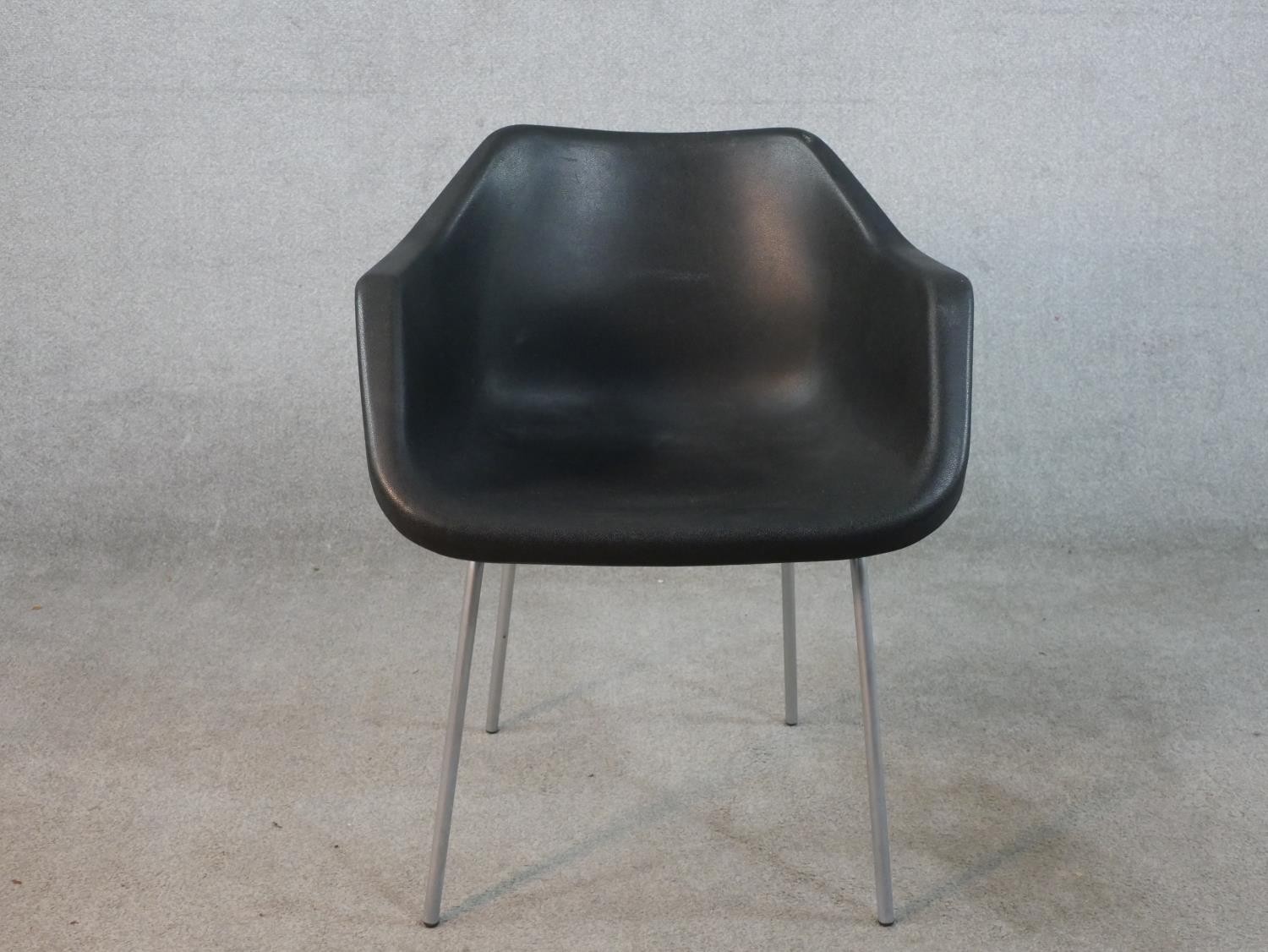 A Robin Day for Hille black plastic tub chair raised on four chrome plated outswept supports,