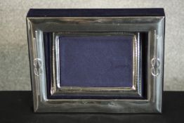 A silver framed blue velvet lined open box with a separate silver photo frame, matching design.