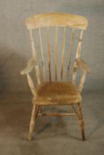 A 20th century stripped pine open arm kitchen Windsor chair raised on turned outswept supports and