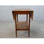 A mid 20th century mahogany drop leaf table with shelf undertier raised on square tapering