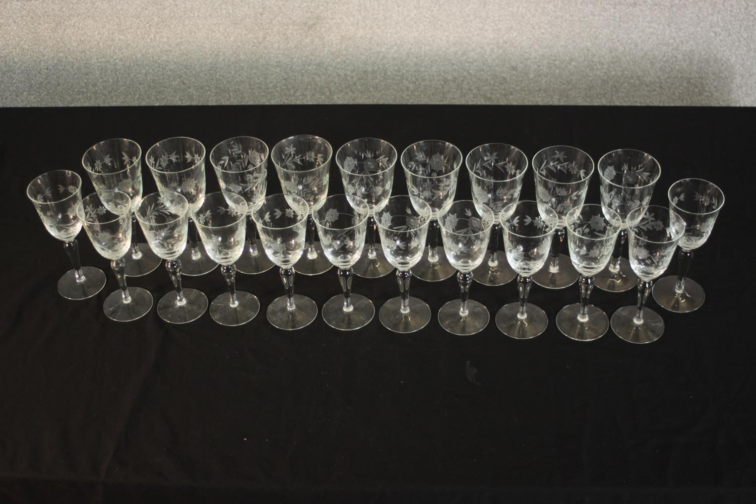 A collection of twenty one etched wine and sherry glasses with floral and foliate design, two