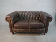 A late 20th century brown leather two seater Chesterfield sofa, with buttoned back and arms and