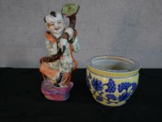 Chinese porcelain figure of a child holding a rui septre; together with a Chinese yellow pottery