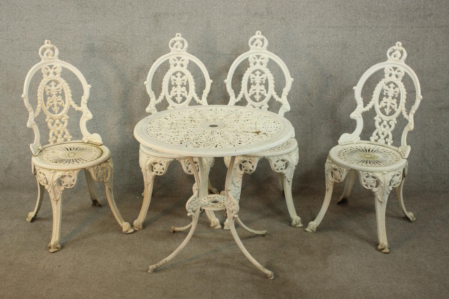 A Victorian style white painted wrought iron garden set comprising of matching four chairs and a