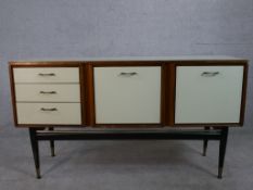 A 1960s white formica Stonehill Furniture sideboard, with a fall front drinks cabinet flanked by