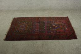 An Eastern / Persian ground red handmade rug with central arch decoration within geometric woven