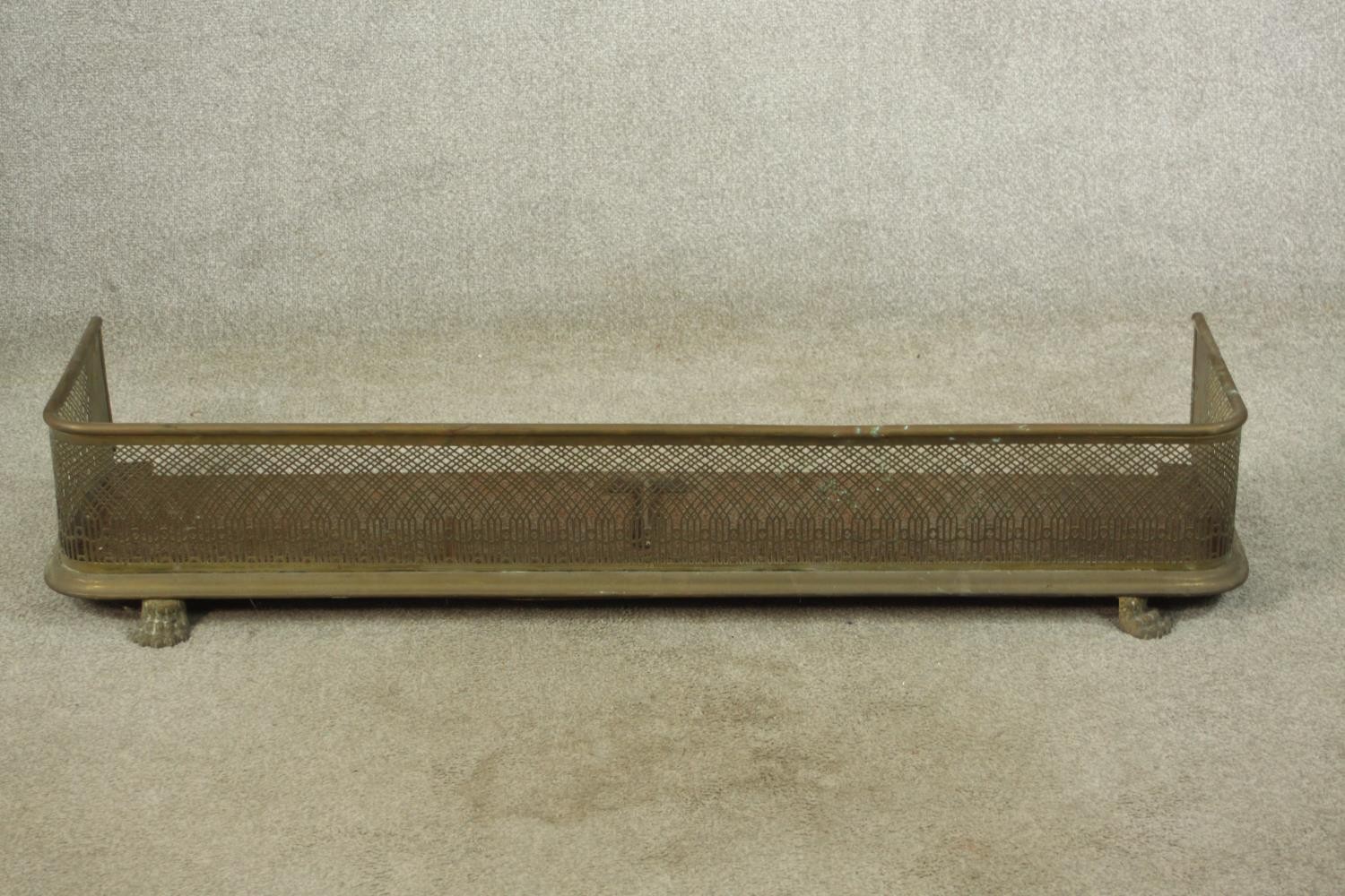 A late 19th century pierced brass fender raised on lion law feet. H.19 W.127 D.34cm.