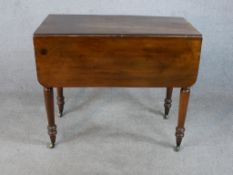 A George III mahogany Pemborke style dropflap table raised on turned legs terminating in casters.