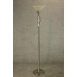 A contemporary polished and brushed steel floor standing uplighter lamp, with a glass shade over