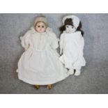 Two 19th century dolls, one craved and painted in a lace bonnet and dress with glass eyes, the other