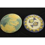 Two large glazed ceramic platters, one decorated with two fish and one with a blue and yellow