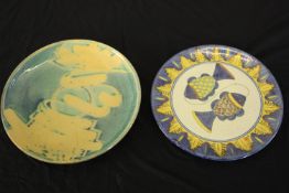 Two large glazed ceramic platters, one decorated with two fish and one with a blue and yellow