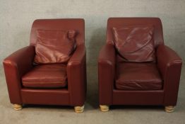 A pair of contemporary brown leather armchairs, with a loose seat and back cushion, on turned pine