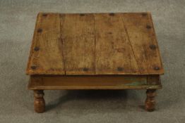 An Indian hardwood low square ceremonial table set with rivet detail, raised on four turned supports