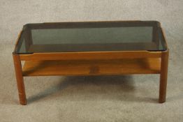 A circa 1960s Myer teak coffee table, of rectangular form with a smoked glass top over an undertier,