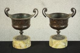 A matched pair of late 19th century Art Nouveau copper twin handled urns cast with Classical