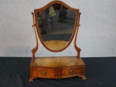 A George III style mahogany toilet mirror, with a shield shaped mirror, the serpentine base with two