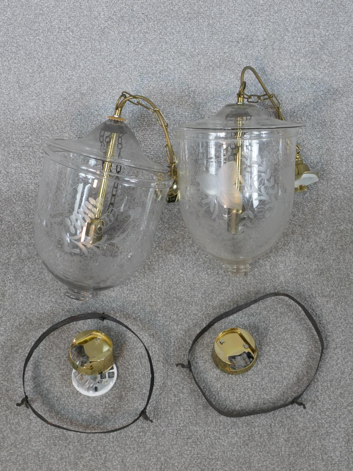 A pair of contemporary Hundi style glass storm lanterns, with brass fittings, the bell shaped