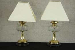 A pair of Victorian brass oil lamps converted to electricity, each with a glass reservoir, on a