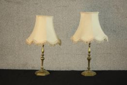 A pair of brass candlestick form table lamps, with turned stems on hexagonal bases, with shades. H.