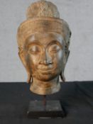 A replica patinated spelter model of a female Buddha head raised on painted wooden base. H.32 W.15