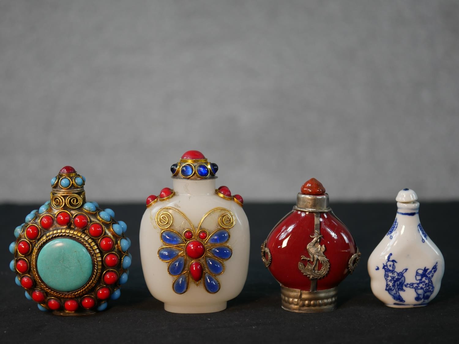 Four 20th century Chinese snuff bottles, one white porcelain with blue figural printed design, a