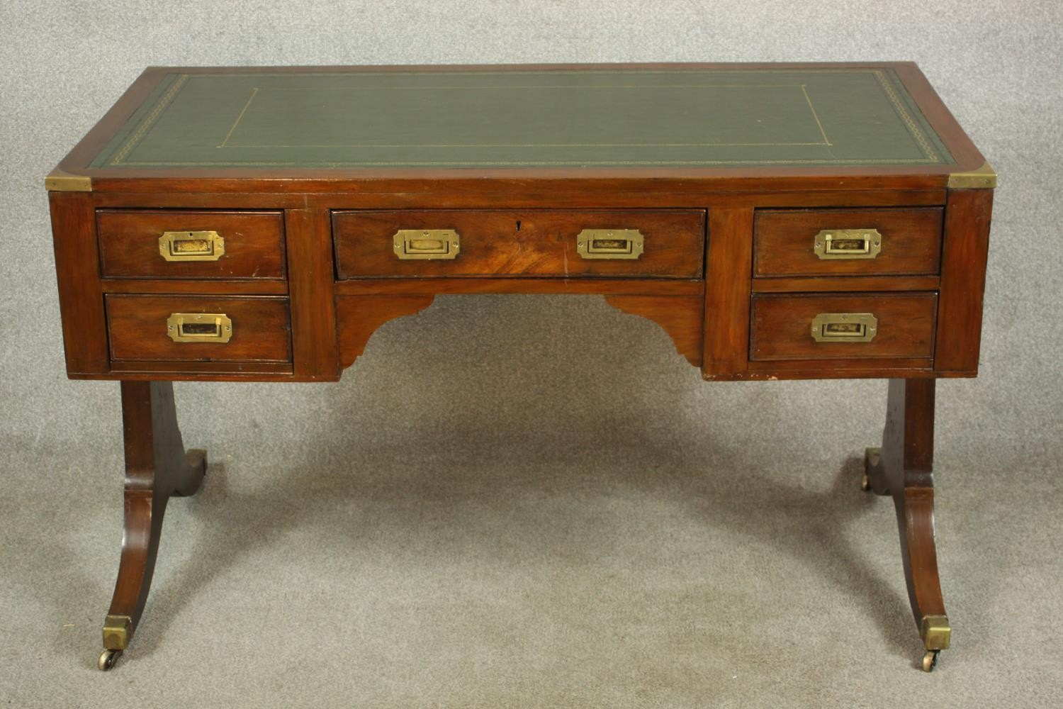 A contemporary mahogany Chinese style leather inset writing table with brass campaign style