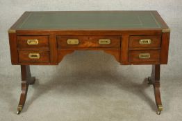 A contemporary mahogany Chinese style leather inset writing table with brass campaign style