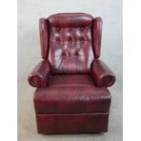 A 20th century oxblood leather Chesterfield style reclining armchair raised on casters.