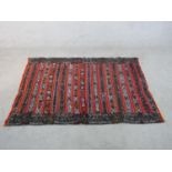 A 20th century red ground Eastern Kelim with stripes of geometric pattern in various colours L.165