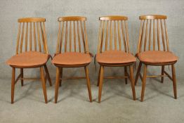 A set of four light elm Ercol stick back Goldsmith dining chairs raised on splayed supports with