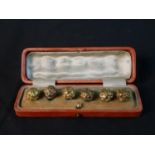 A leather cased set of six 19th century Chinese gilt metal carved floral design robe buttons, one