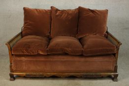 An early 20th century carved mahogany framed and bergère three seater settee with scroll arms and