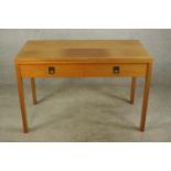 A mid 20th century oak two drawer drop leaf table with campaign style brass handles raised on square
