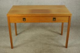A mid 20th century oak two drawer drop leaf table with campaign style brass handles raised on square