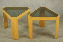 A contemporary pair of beech framed triangular framed side tables with smokey glass inserts raised