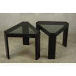 A pair of contemporary black painted triangular framed side tables with glass inserts raised on