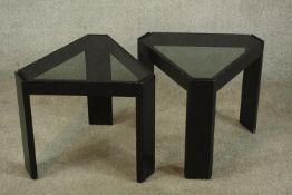 A pair of contemporary black painted triangular framed side tables with glass inserts raised on