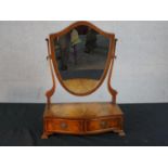 A George III style mahogany toilet mirror, with a shield shaped mirror, the serpentine base with two
