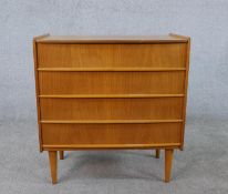 A circa 1960s teak chest of four long drawers, on cylindrical tapering legs. H.64 W.60 D.33cm