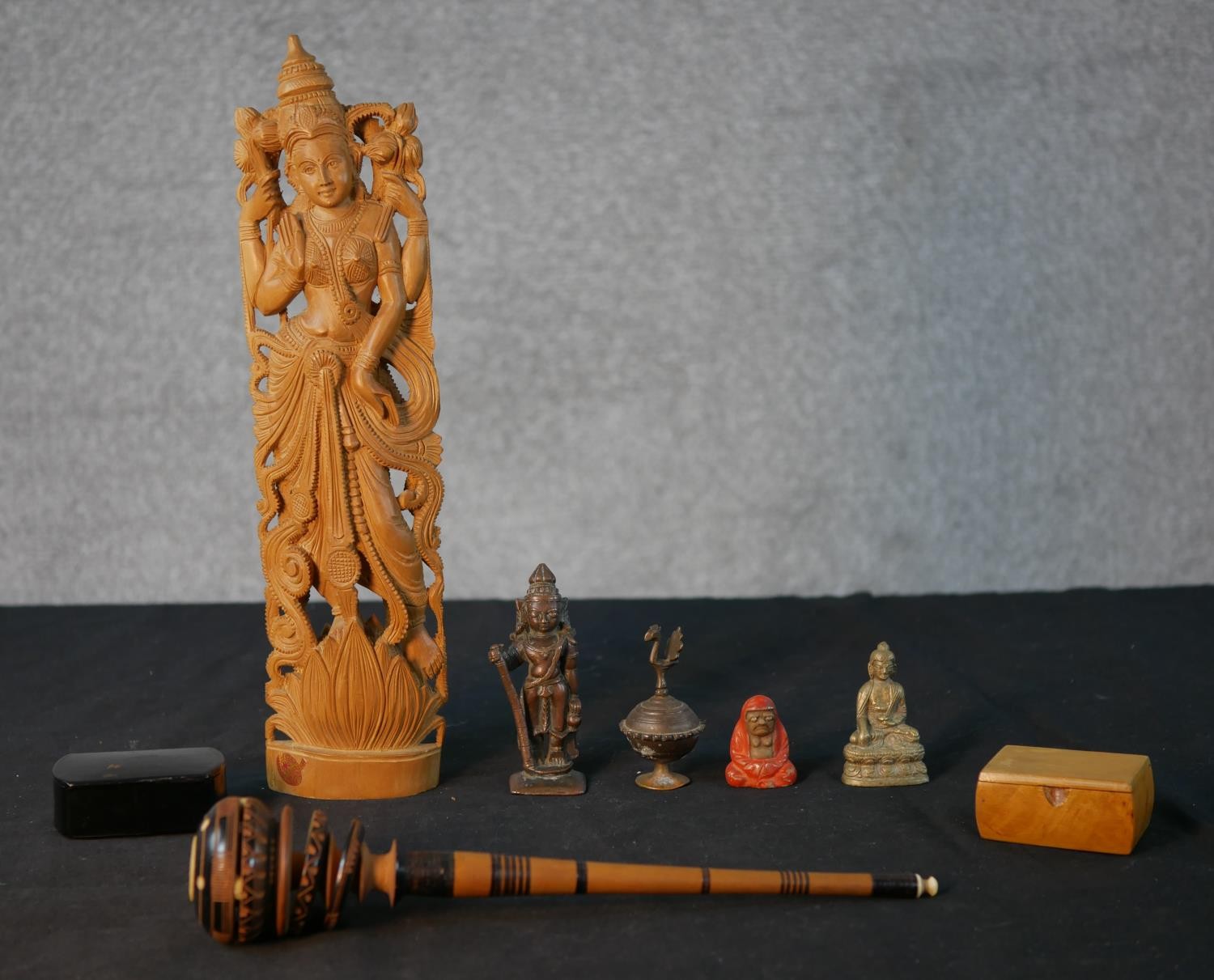 A collection of figures and boxes, including a bronze Indian deity, brass Buddha, carved hardwood